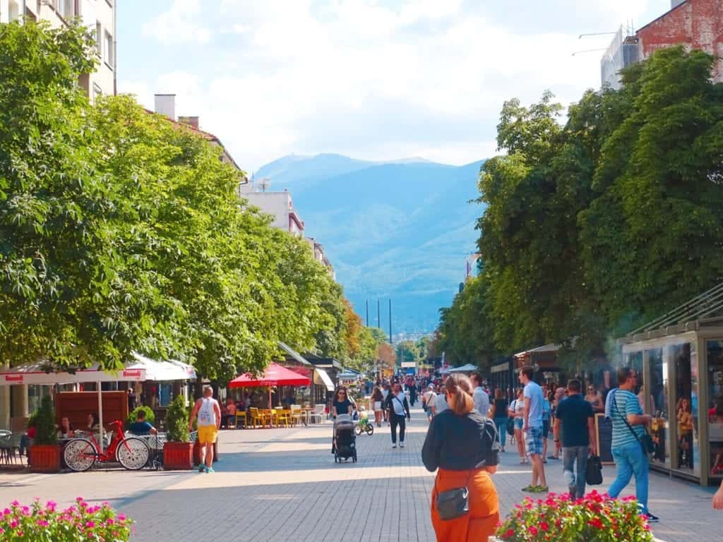 People walking through Sofia city centre with view of Vitosha Mountain behind