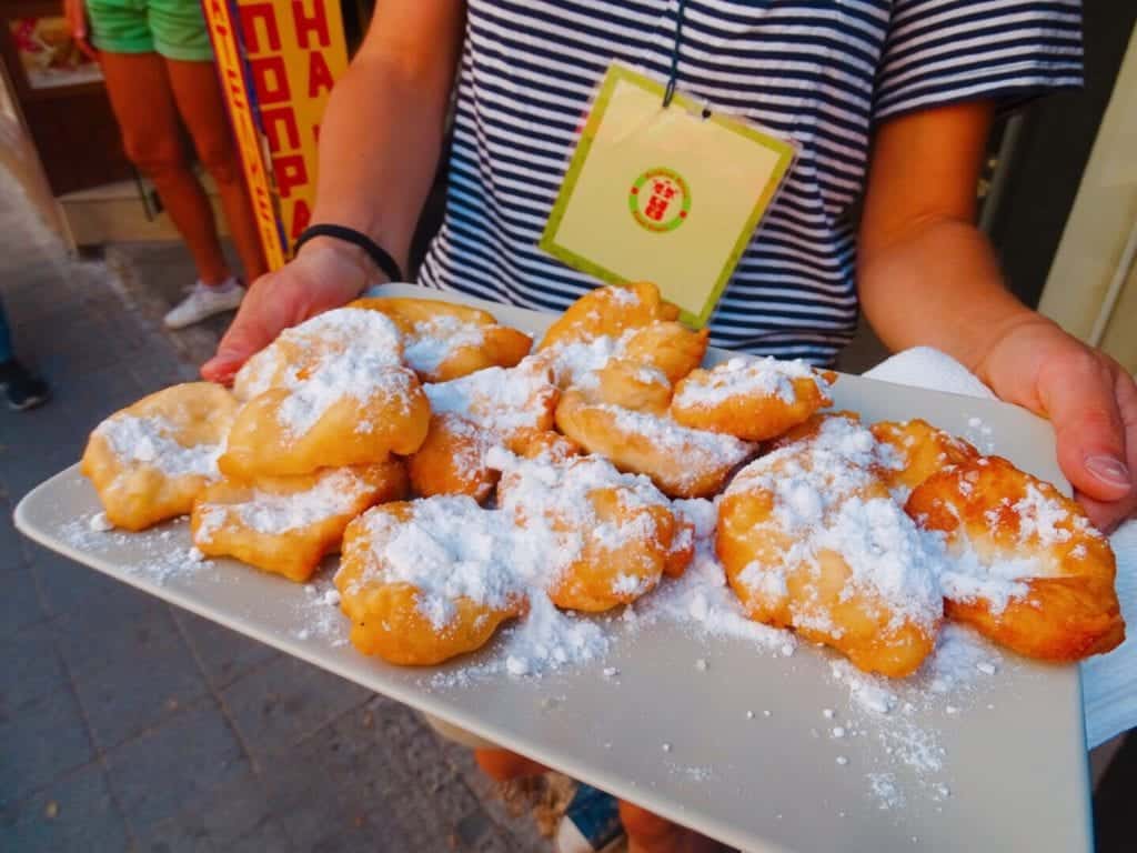 Woman holding plate of Bulgarian desserts dusted with icing sugar Sofia