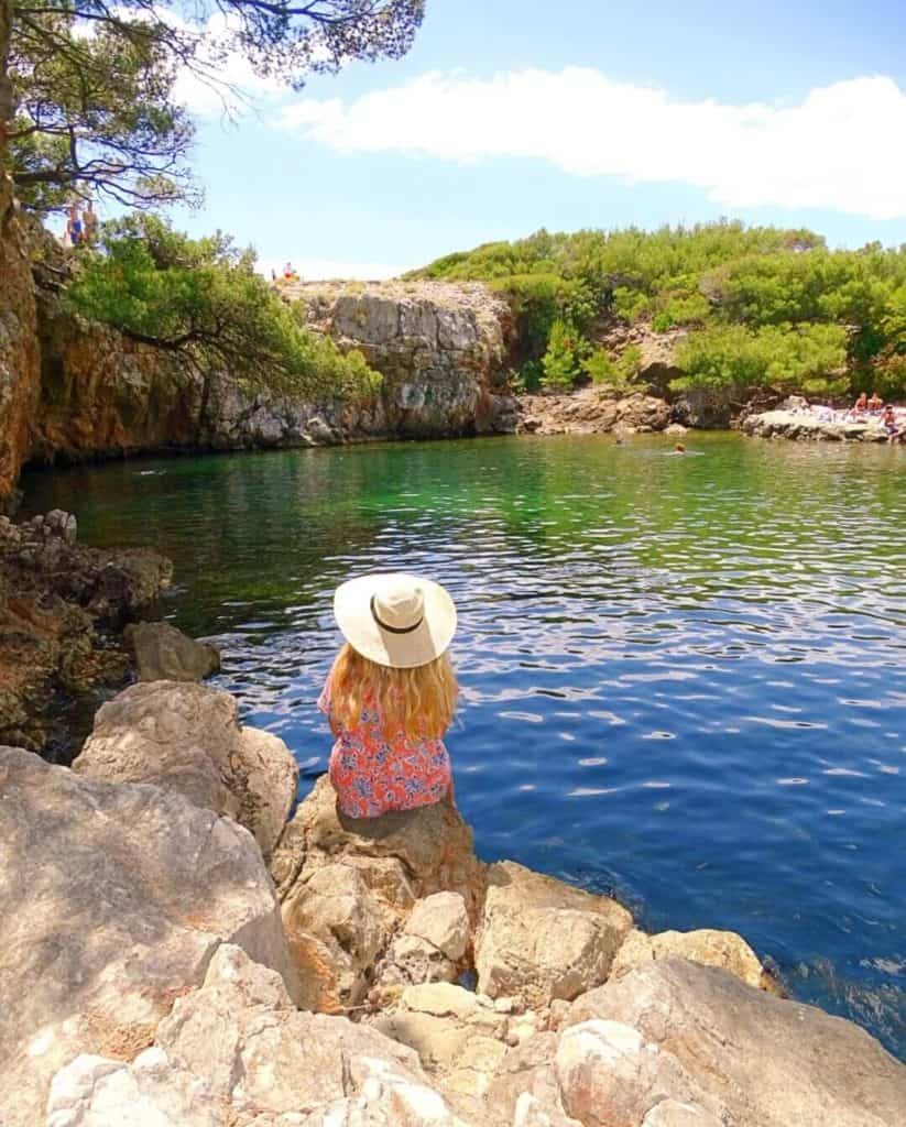 Girl with hat beside blue and green water hole