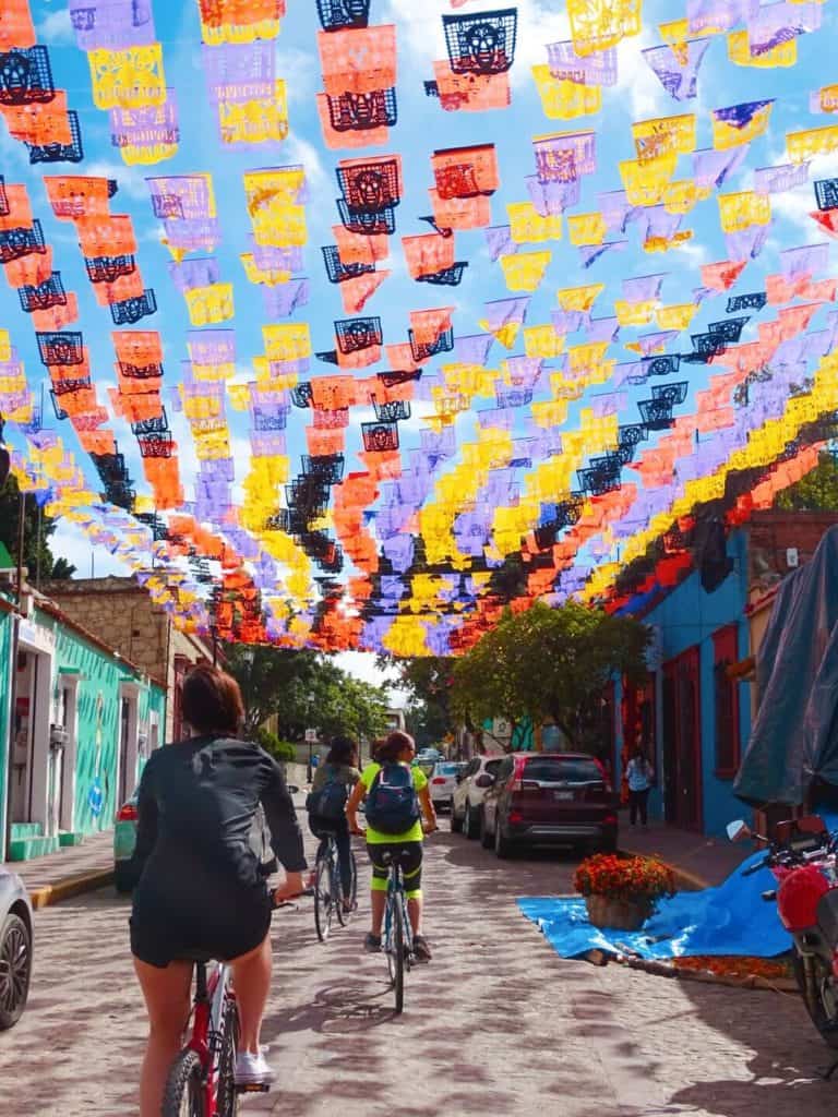 People cycling under colourful flags Oaxaca