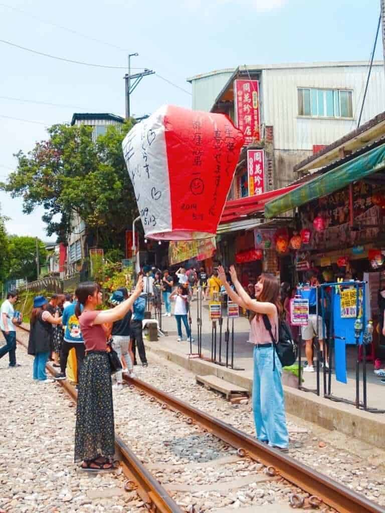 Girls releasing giant lantern from Shifen railway tracks 