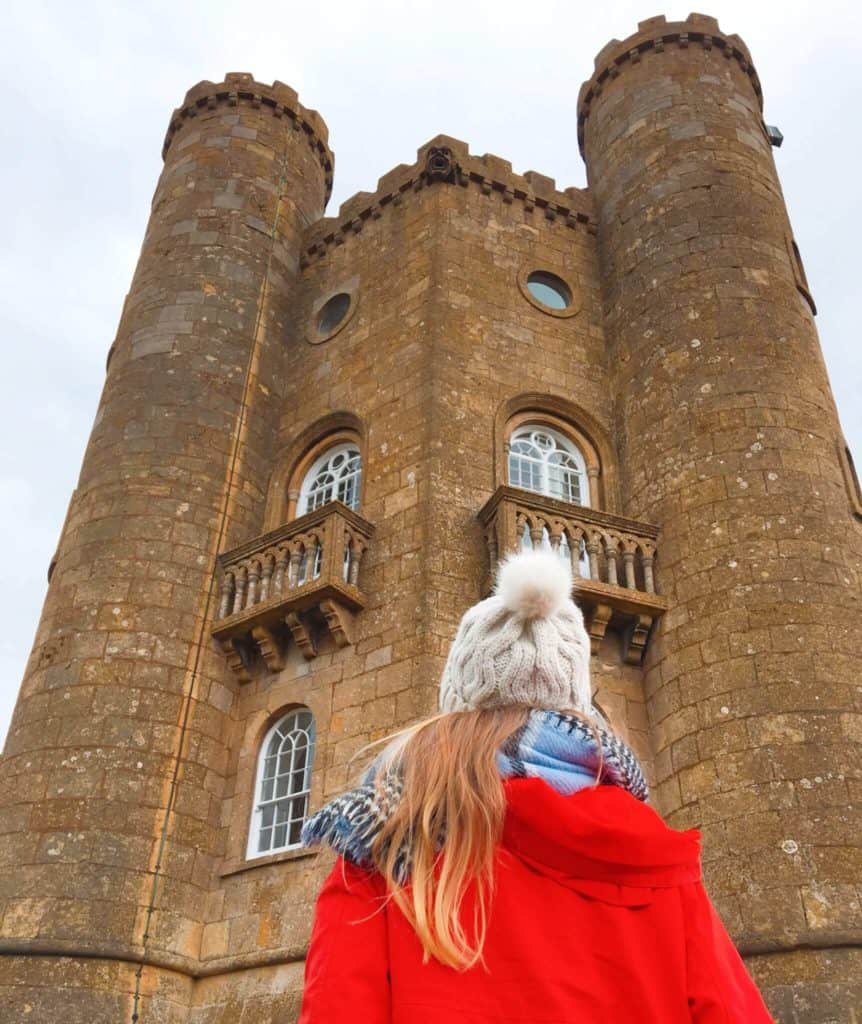 Girl in red coat looking up at Broadway Tower 