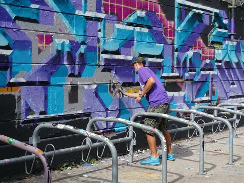Man in purple street doing graffiti